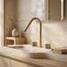 Kilde brass bathroom faucet in brushed gold on a travertine and oak bathroom counter