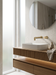 Grifo de baño dorado cepillado en un baño moderno: Idun de pared sobre lavabo blanco en mueble estriado